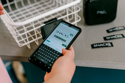 Hand typing 'snacks' on smartphone for custom labels