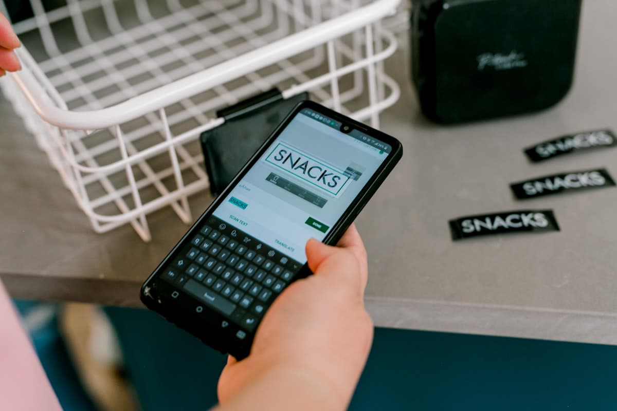 Hand typing 'snacks' on smartphone for custom labels