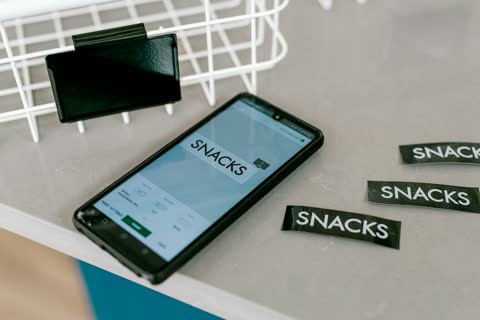 Black smartphone displays "snacks" next to snack labels