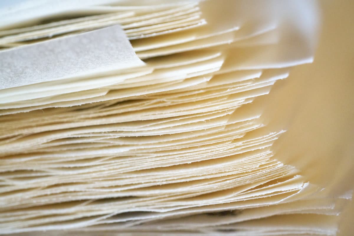 A stack of thin white paper sheets with rough edges