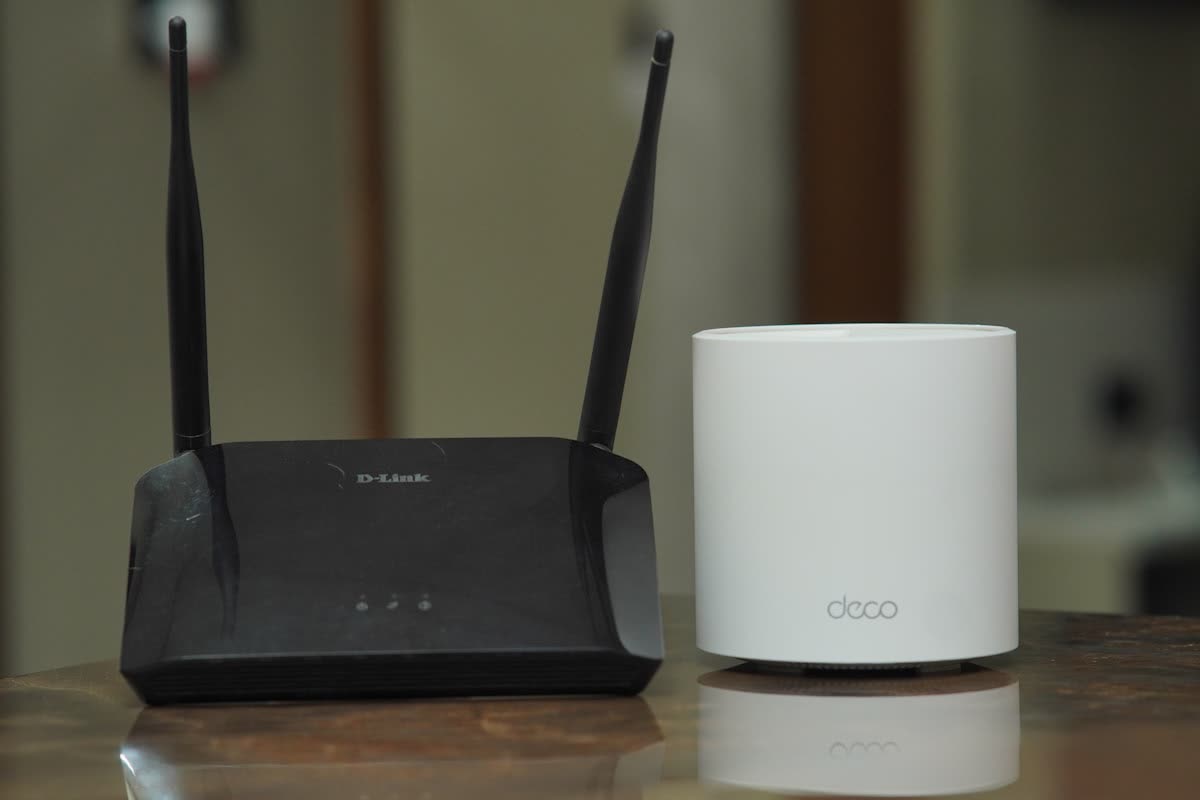 Black wireless router next to a mesh Wi-Fi unit