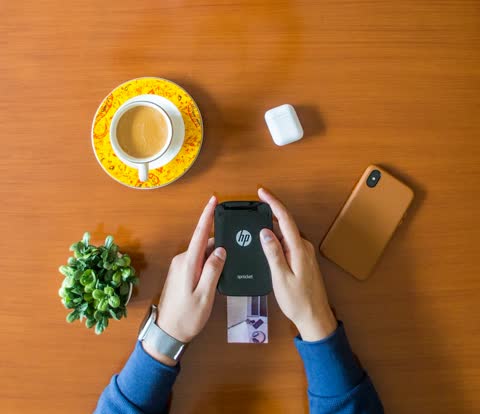 Person holding a smartphone beside a small printed photo