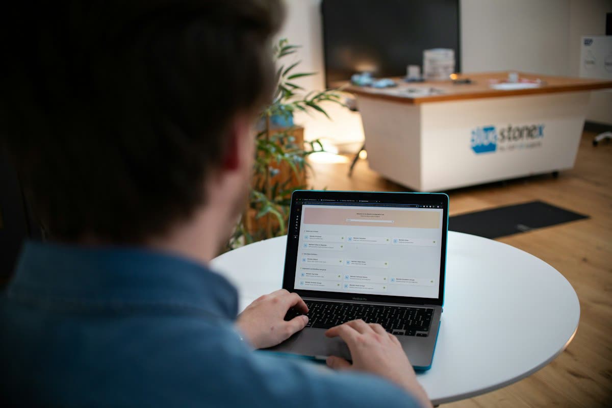 Man typing on laptop at a white table
