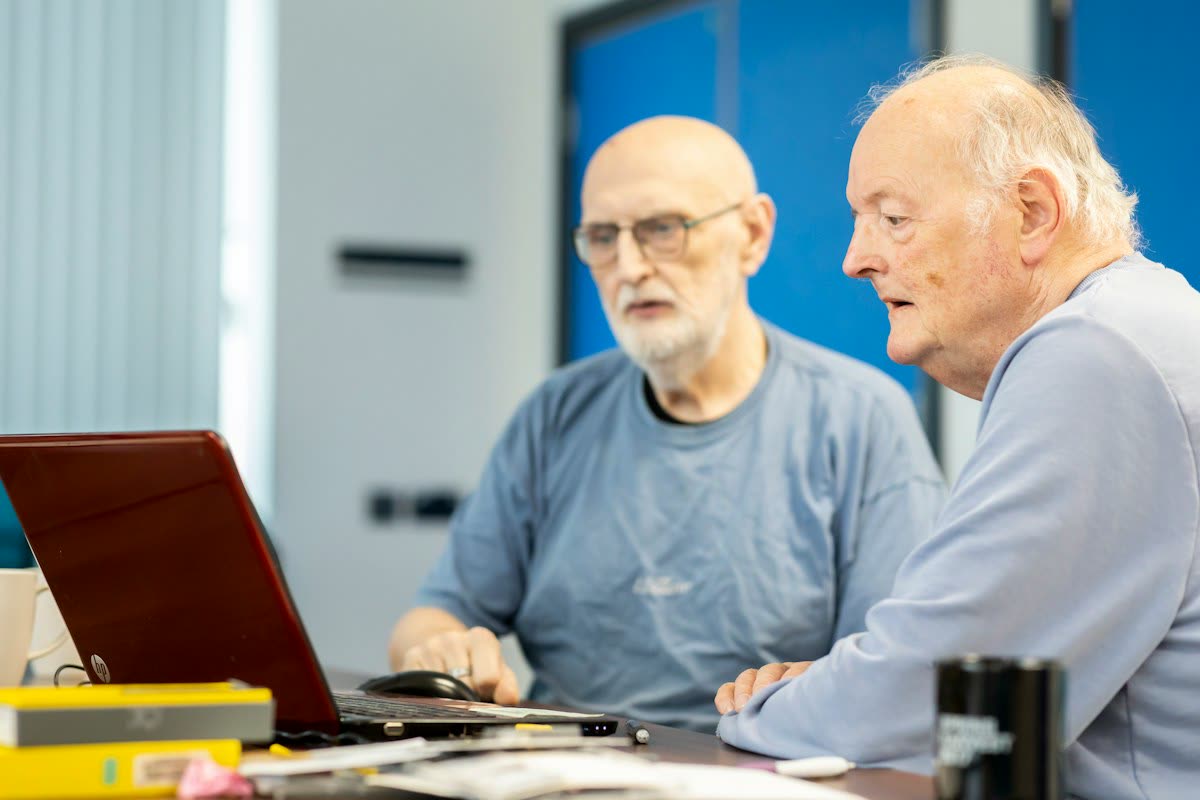 Two older men looking at a laptop together