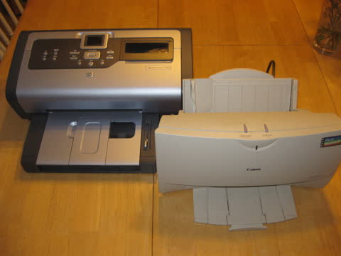 Two inkjet printers side by side on a wooden floor